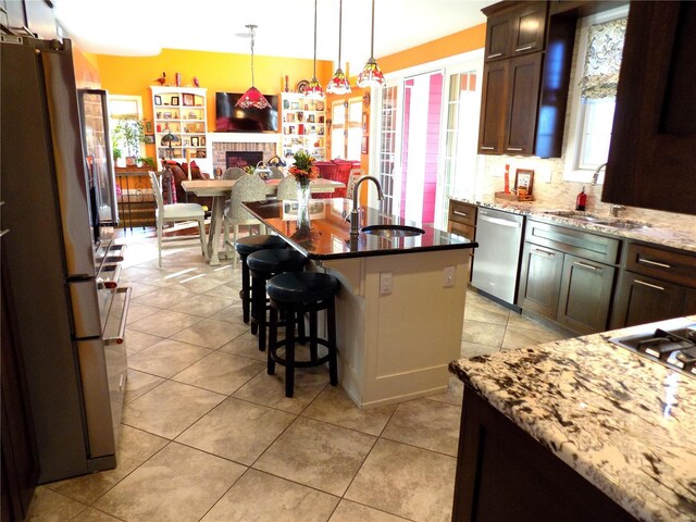 kitchen featuring sink, light stone countertops, stainless steel dishwasher, a fireplace, and fridge