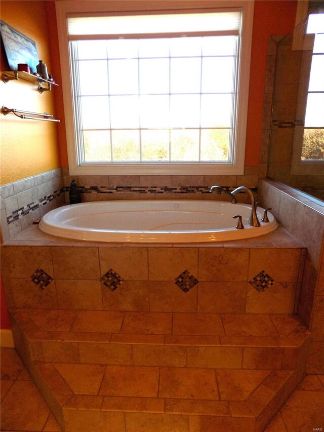 bathroom featuring tiled bath, a healthy amount of sunlight, and tile patterned floors