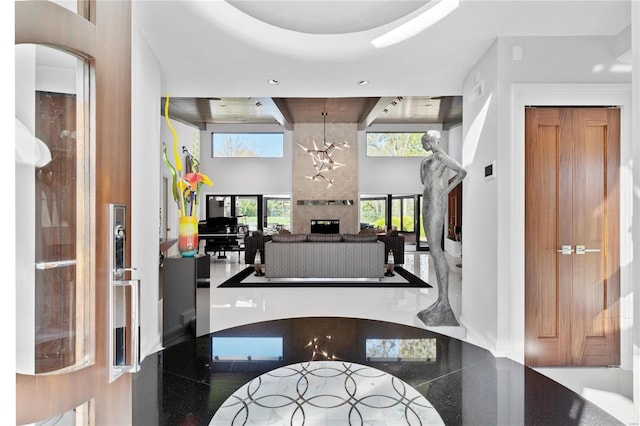 interior space featuring a wealth of natural light, a fireplace, a towering ceiling, and an inviting chandelier