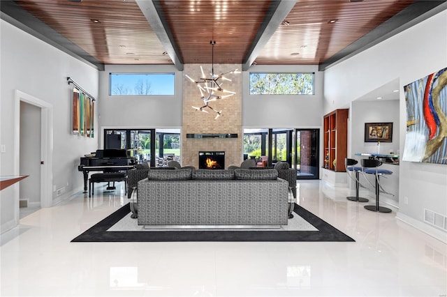 tiled living room featuring a large fireplace, wooden ceiling, a towering ceiling, and an inviting chandelier