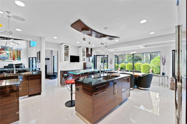 kitchen with a breakfast bar, a large island with sink, hanging light fixtures, and light tile patterned flooring