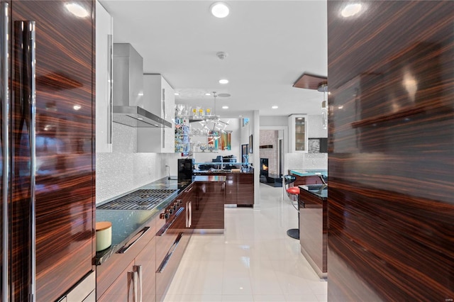 kitchen featuring wall chimney exhaust hood, light tile patterned floors, tasteful backsplash, stainless steel fridge, and white cabinets