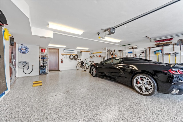 garage featuring a garage door opener and a wall mounted AC