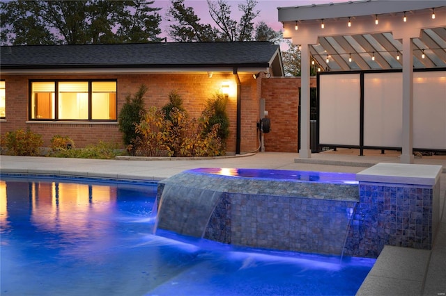 pool at dusk with a jacuzzi and pool water feature