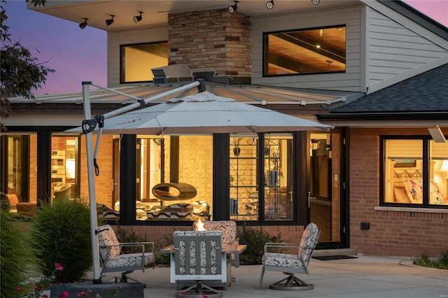 back house at dusk featuring a patio area