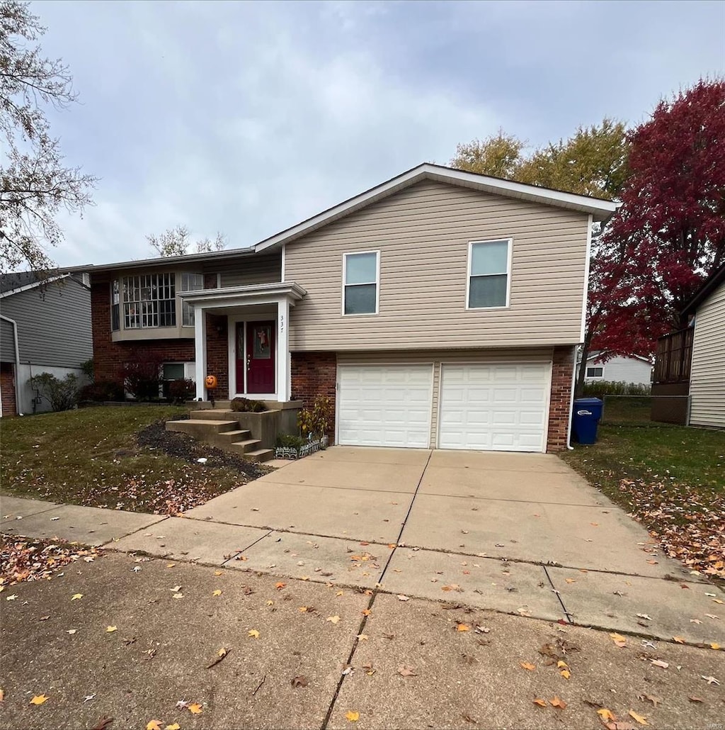 bi-level home featuring concrete driveway, an attached garage, and brick siding