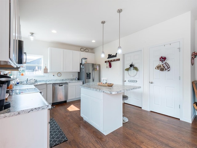 kitchen featuring stainless steel appliances, white cabinetry, decorative light fixtures, dark wood-type flooring, and a center island