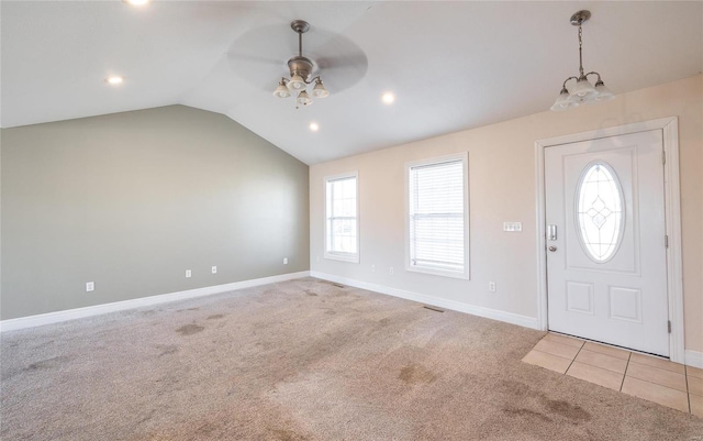 carpeted foyer entrance featuring plenty of natural light, ceiling fan with notable chandelier, and vaulted ceiling