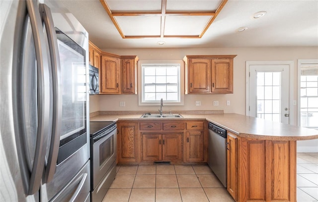 kitchen with kitchen peninsula, sink, light tile patterned floors, and stainless steel appliances