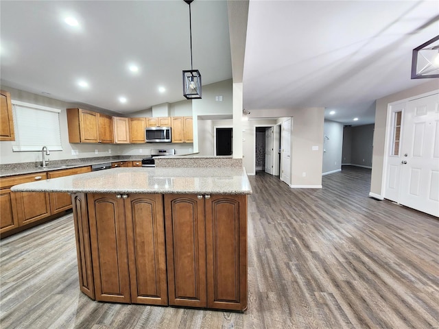 kitchen with a center island, lofted ceiling, decorative light fixtures, stainless steel appliances, and sink