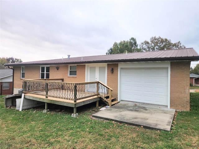 back of house featuring a garage, a wooden deck, and a lawn