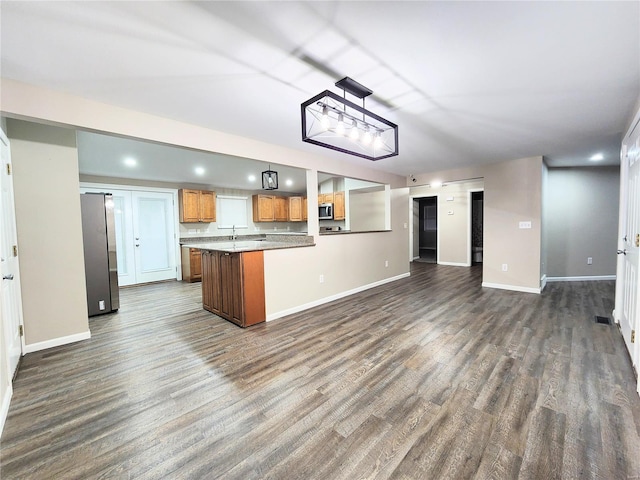 kitchen featuring decorative light fixtures, kitchen peninsula, appliances with stainless steel finishes, and dark hardwood / wood-style floors