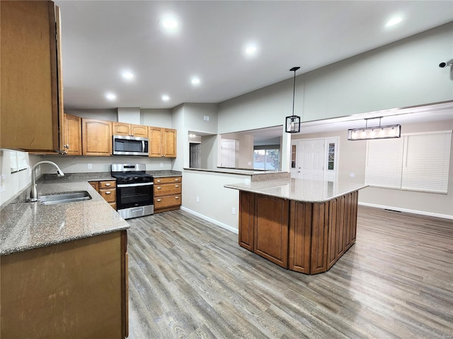 kitchen featuring appliances with stainless steel finishes, light stone counters, decorative light fixtures, and sink