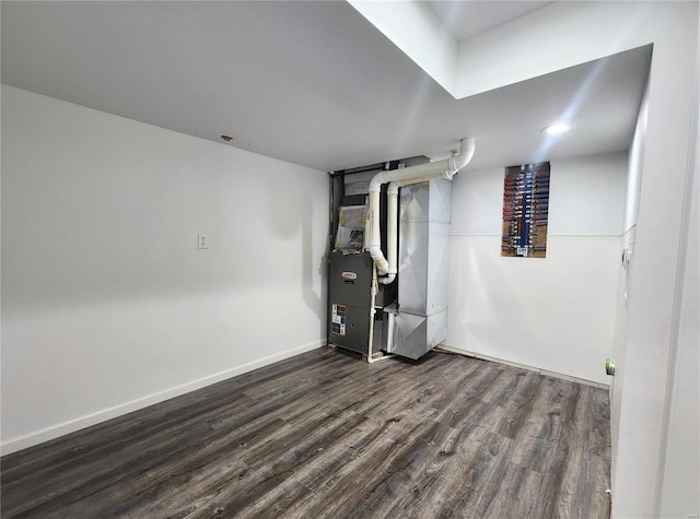 basement with dark hardwood / wood-style flooring and heating unit