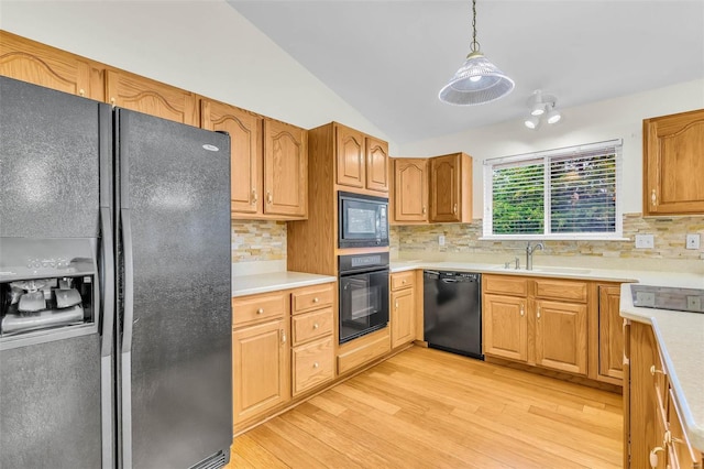 kitchen with lofted ceiling, black appliances, sink, hanging light fixtures, and tasteful backsplash