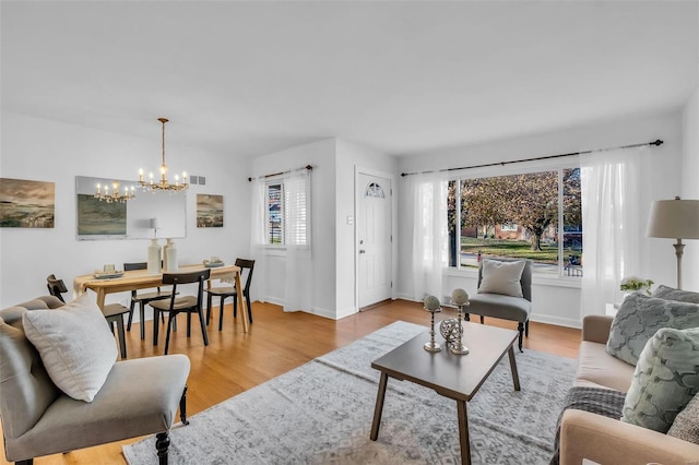 living room with light hardwood / wood-style floors, plenty of natural light, and a notable chandelier