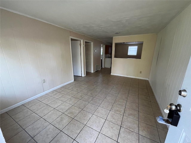 tiled empty room featuring wooden walls