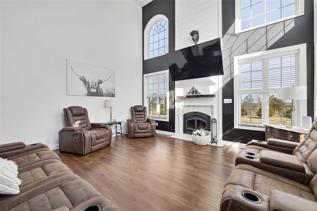 living room with a fireplace with flush hearth, a high ceiling, baseboards, and wood finished floors