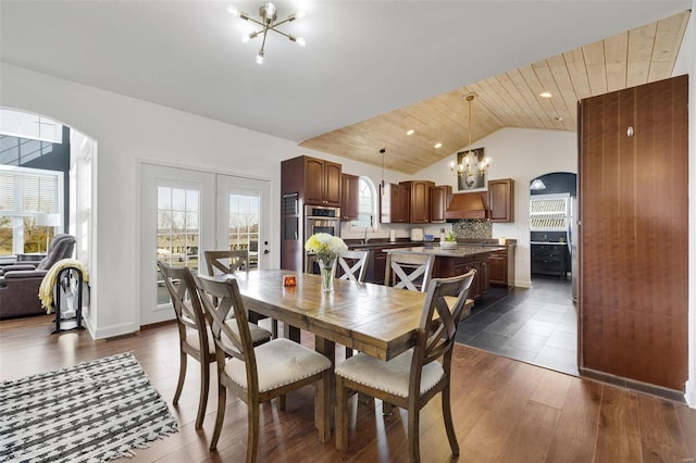 dining room with lofted ceiling, a chandelier, arched walkways, and dark wood-type flooring