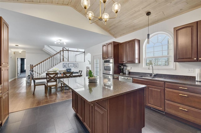 kitchen with lofted ceiling, a kitchen island, a sink, appliances with stainless steel finishes, and pendant lighting