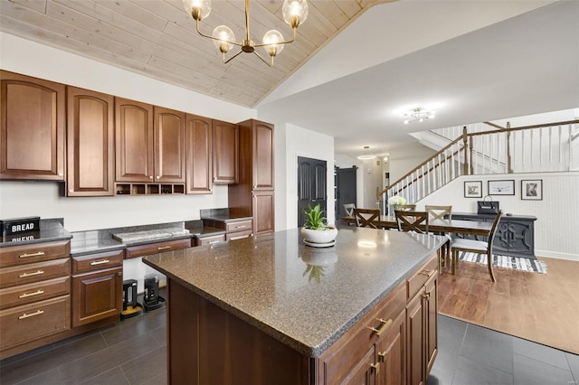 kitchen featuring a chandelier, vaulted ceiling, a center island, open shelves, and dark countertops