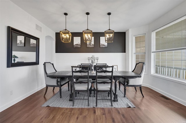 dining space featuring arched walkways, wood finished floors, and visible vents