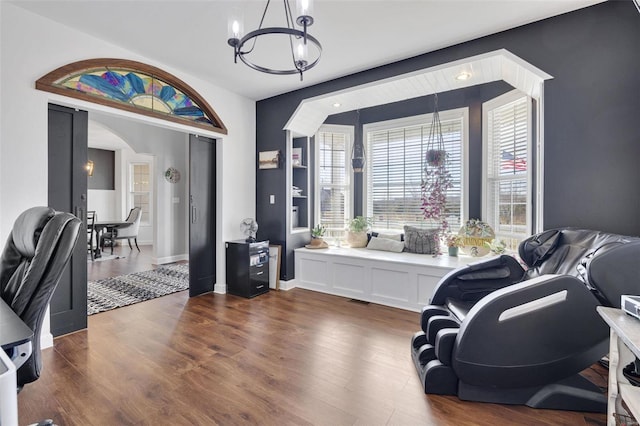 sitting room with a chandelier, arched walkways, dark wood-type flooring, and baseboards