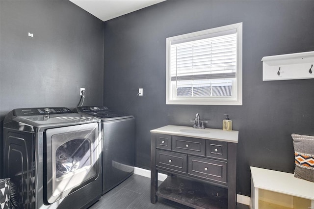 washroom with laundry area, dark wood-style flooring, a sink, baseboards, and independent washer and dryer