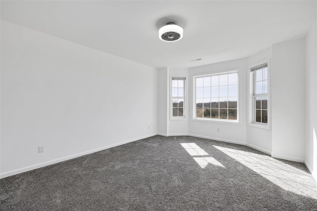 empty room with dark colored carpet and baseboards