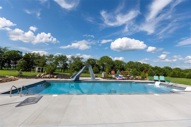 outdoor pool with a water slide and a patio