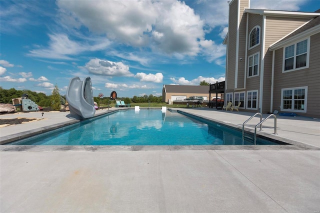 pool with a water slide and a patio