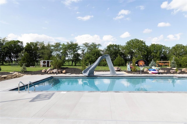 pool featuring a water slide and a patio area