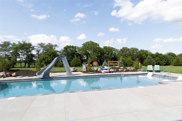 outdoor pool with a patio area and a water slide