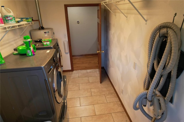 laundry room with electric water heater, washer and clothes dryer, and light tile patterned flooring