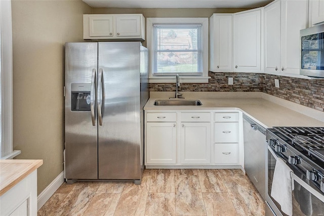 kitchen featuring stainless steel appliances, white cabinetry, and sink