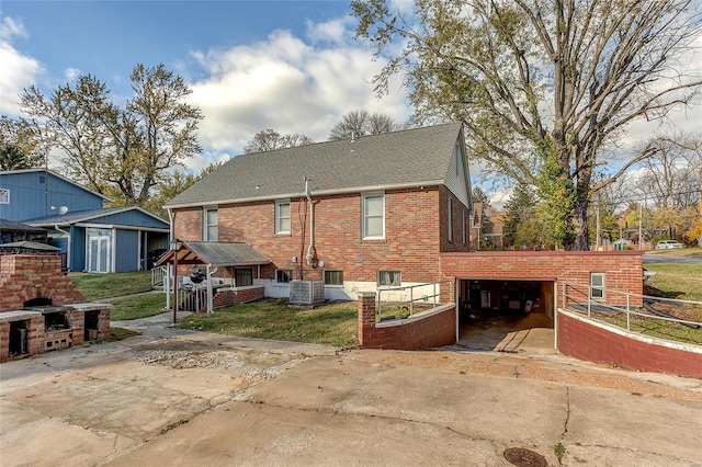 back of property with a garage, cooling unit, an outbuilding, and a lawn