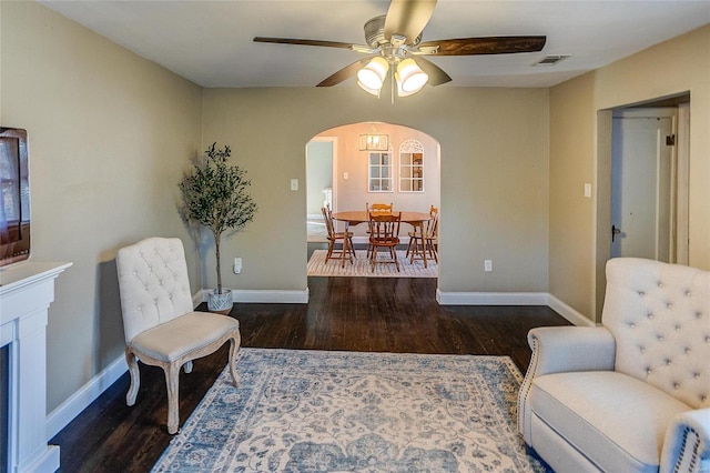 living area with dark wood-type flooring and ceiling fan