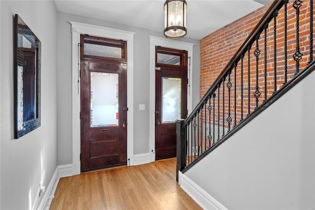 entrance foyer with light wood-type flooring and brick wall