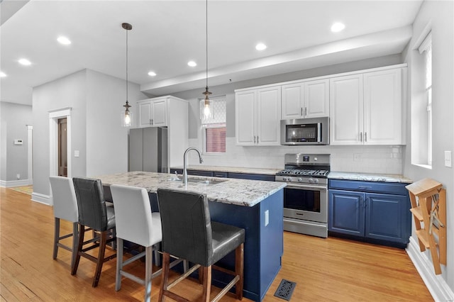 kitchen featuring white cabinetry, sink, stainless steel appliances, light hardwood / wood-style flooring, and an island with sink