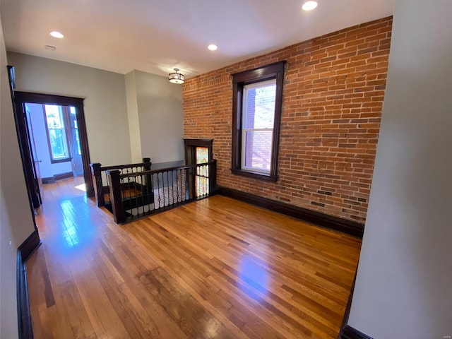 empty room with wood-type flooring and brick wall