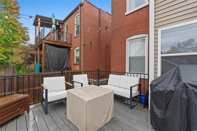 wooden deck with an outdoor hangout area and grilling area