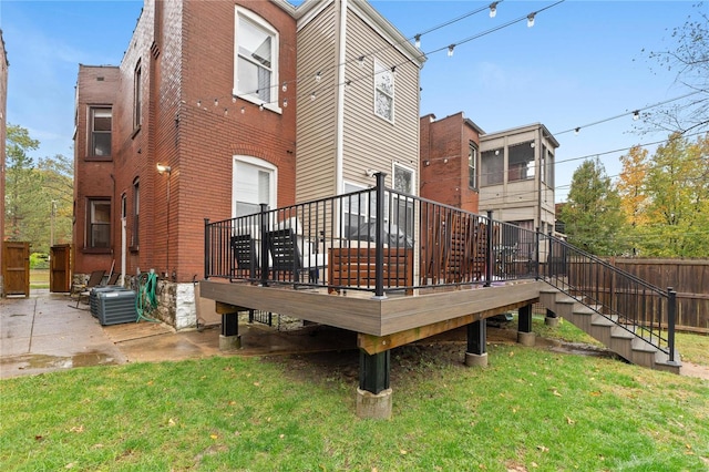 rear view of property featuring a lawn, central AC unit, and a deck