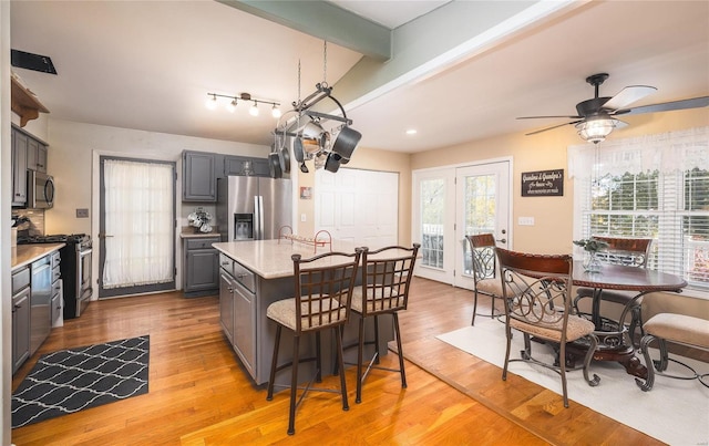 kitchen with stainless steel appliances, a kitchen island, a wealth of natural light, and light hardwood / wood-style flooring