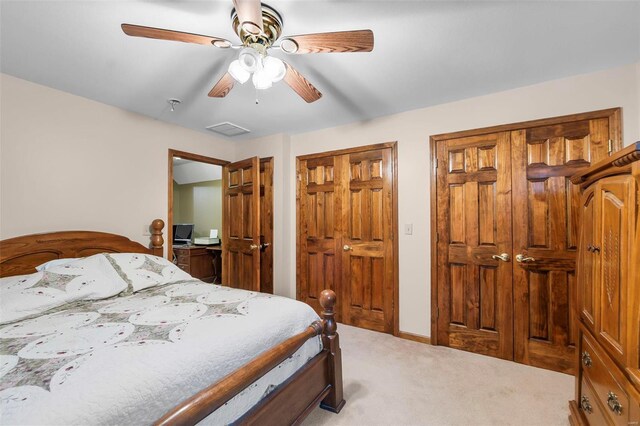 carpeted bedroom with two closets and ceiling fan