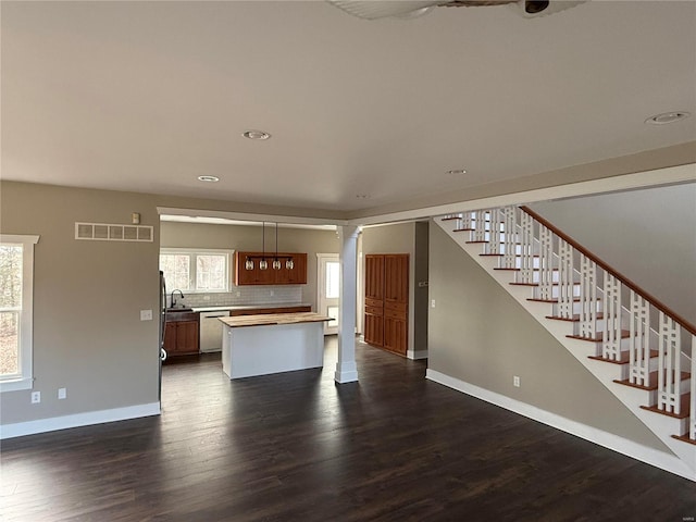 kitchen with ornate columns, dishwasher, dark hardwood / wood-style floors, decorative light fixtures, and decorative backsplash