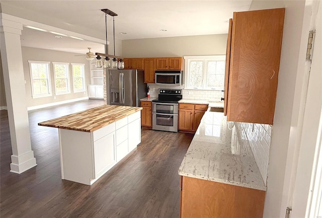 kitchen with a center island, dark hardwood / wood-style floors, pendant lighting, decorative backsplash, and appliances with stainless steel finishes