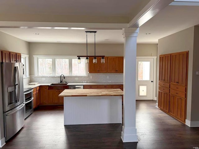 kitchen featuring appliances with stainless steel finishes, dark wood-type flooring, sink, pendant lighting, and a center island