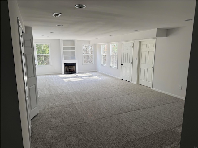 unfurnished living room featuring carpet flooring and built in features