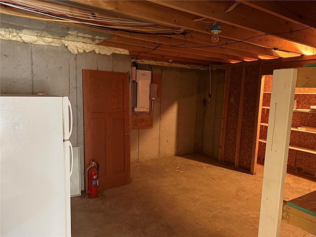 basement featuring white refrigerator and electric panel