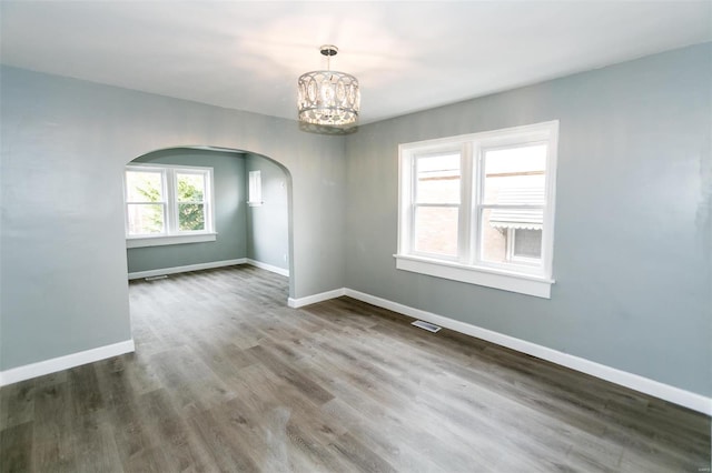 unfurnished room featuring hardwood / wood-style floors and a chandelier